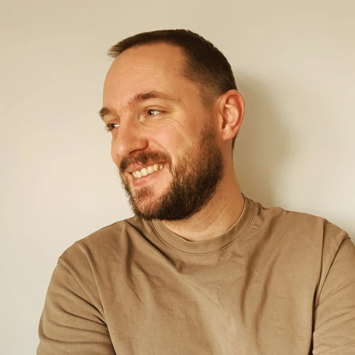 Luke Tyler smiling, arms folded, in a plain T-shirt